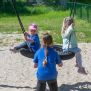 Single Swing (BNS 90cm) üzerinde sallanan çocuklar ve oyun alanı ekipmanı.