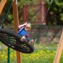 Single Swing (BNS 90cm) üzerinde sallanan çocuk ile ahşap çerçeveli yuvarlak salıncak.